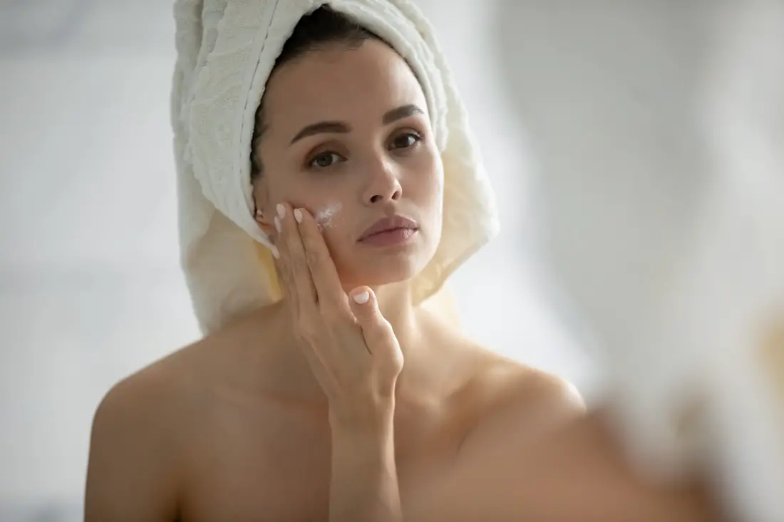 Careful young woman with sensitive skin applying cream on chick