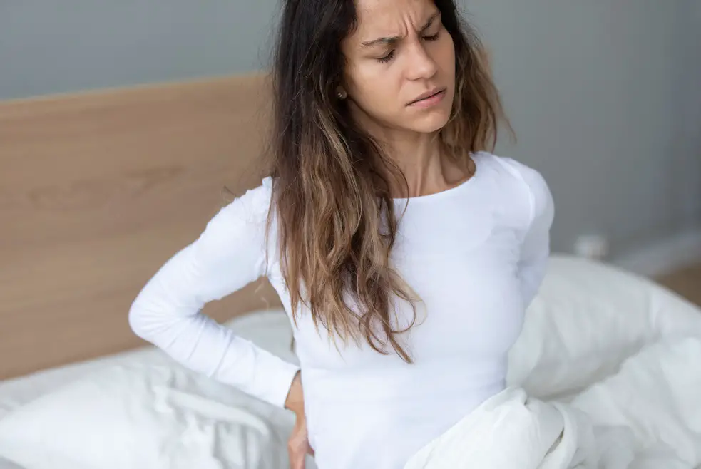 Young woman awakening feeling lower back pain