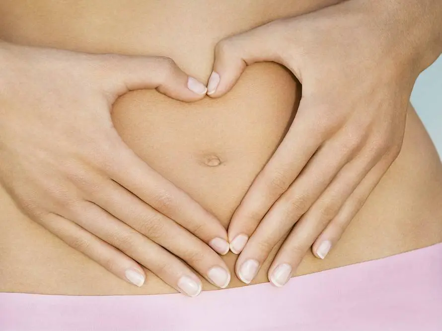 Closeup on hands framing a heart on a woman belly