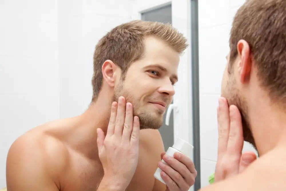 Man,Looking,Into,The,Mirror,And,Applying,Aftershave